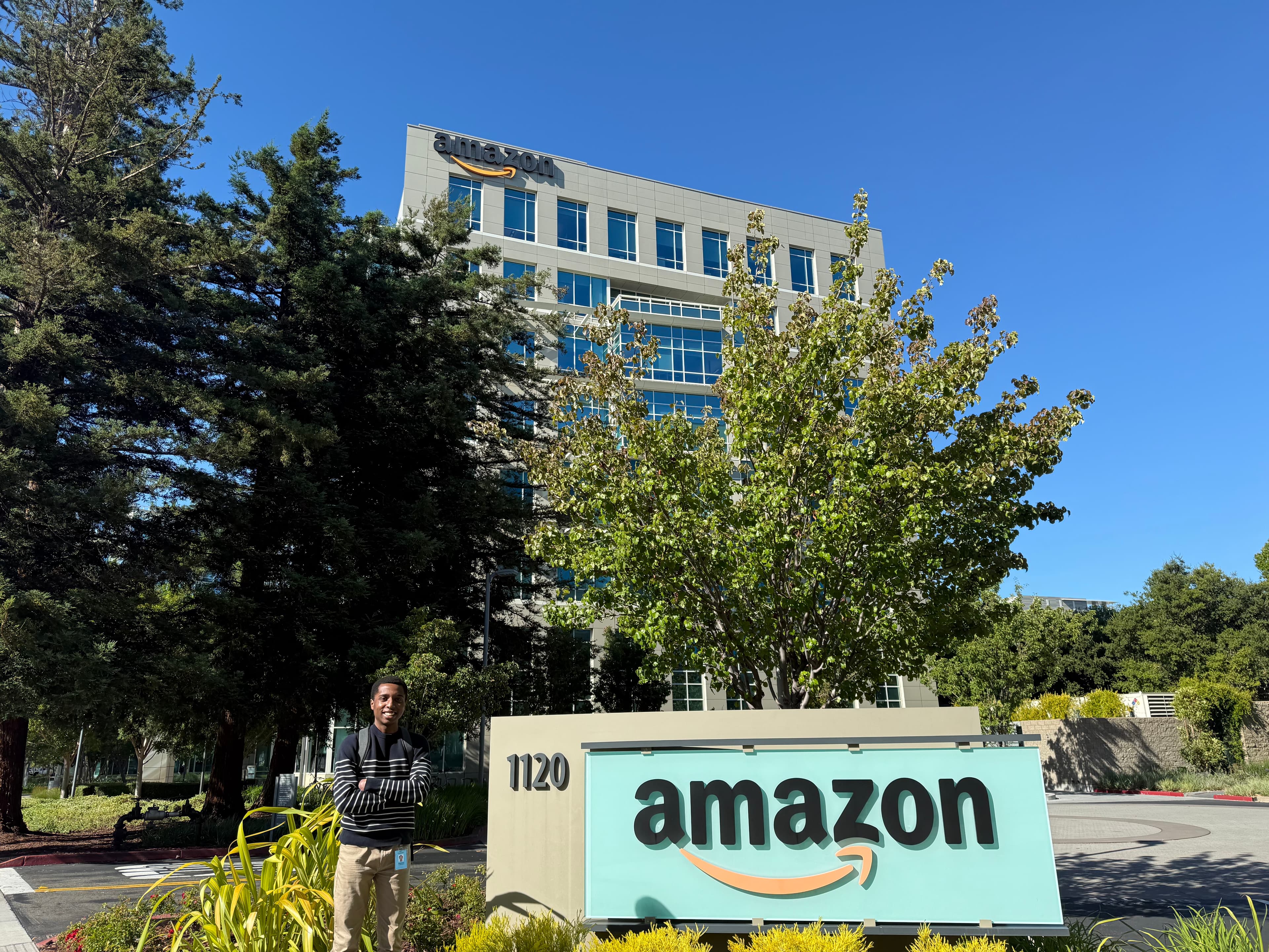 A person standing beside an Amazon sign outside an office building