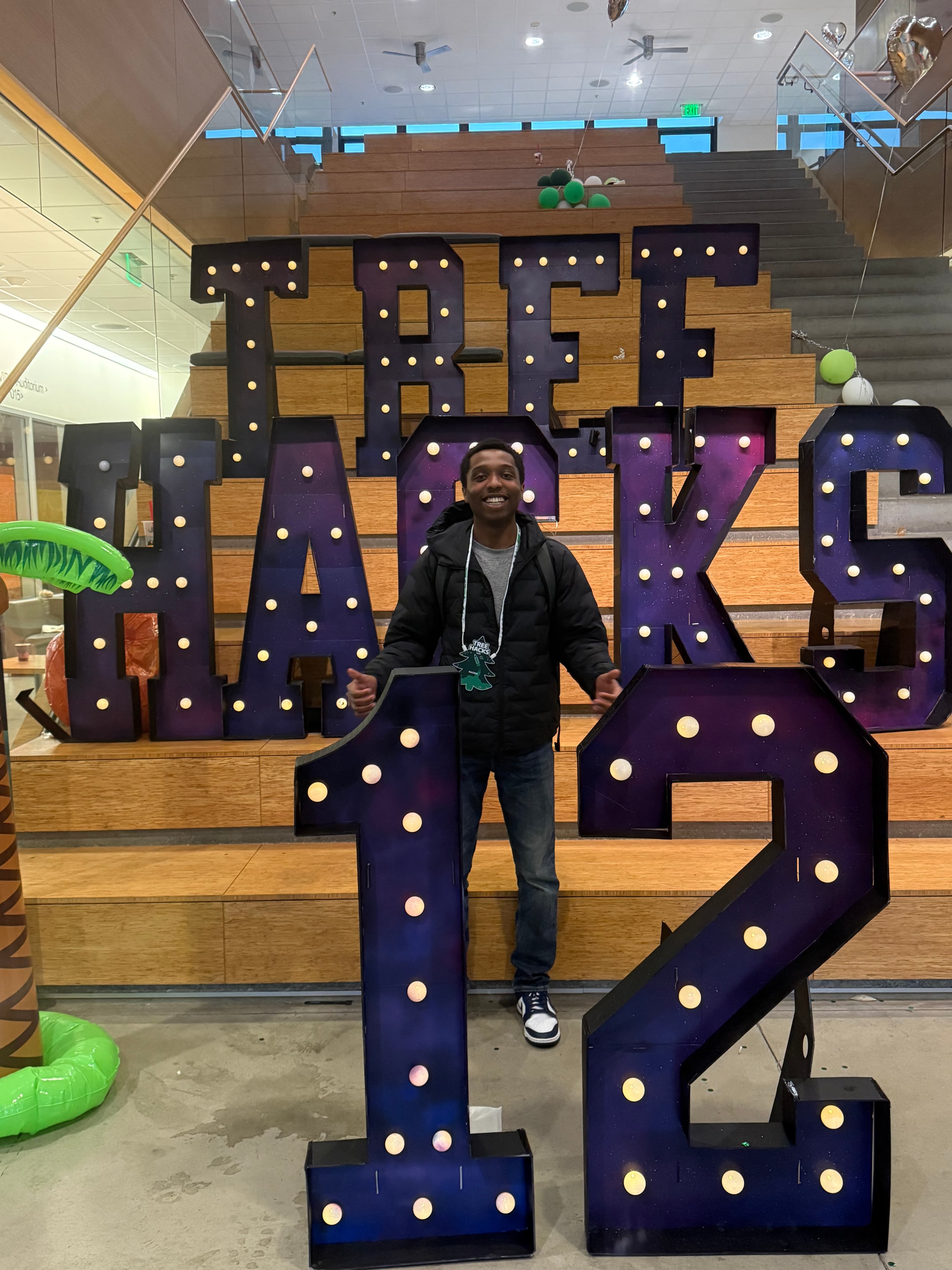 A person standing in front of illuminated TreeHacks lettering
